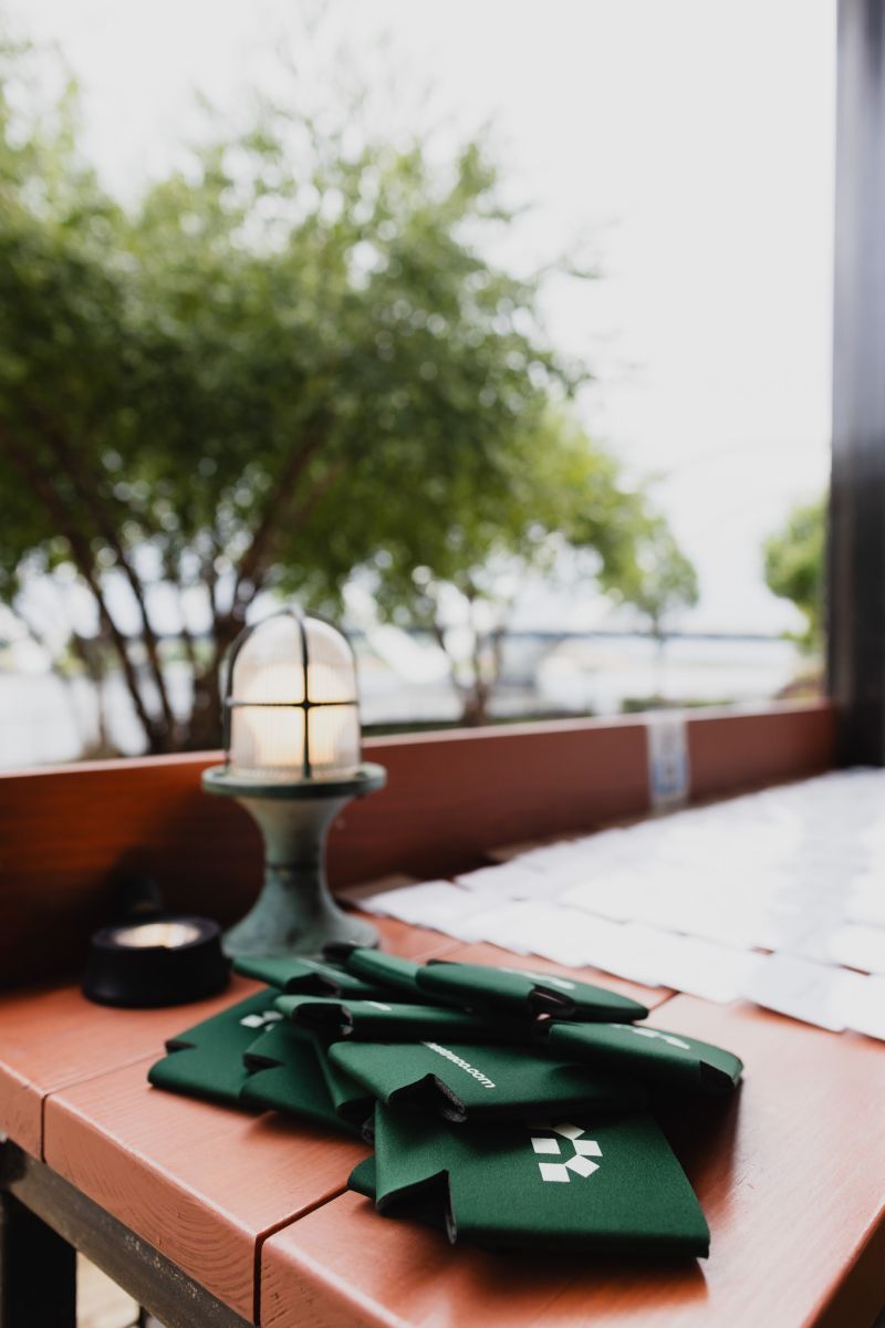 Green Orchestra-branded koozies on a wooden bench