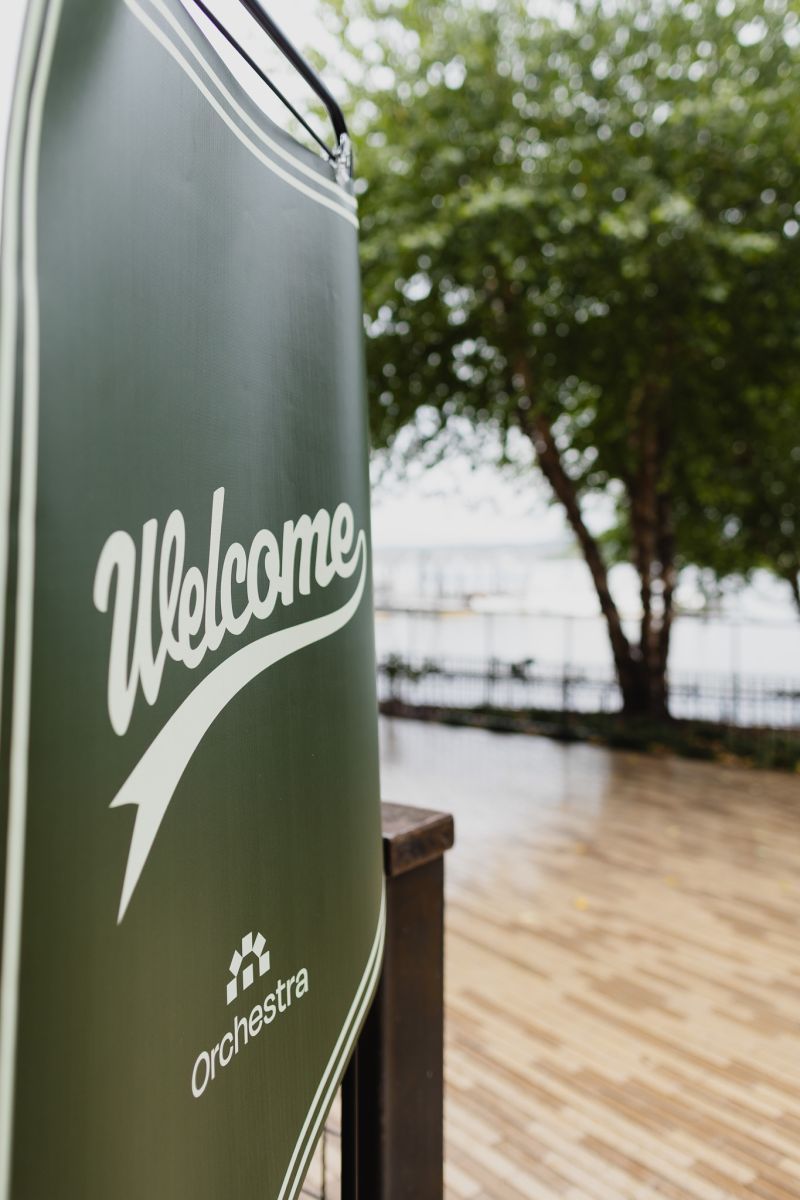 A green Orchestra 'Welcome' sign on a waterfront deck